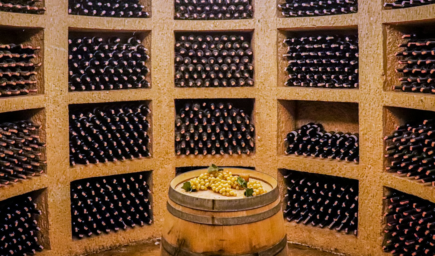 Botte di vino in legno con uva in una cantina.