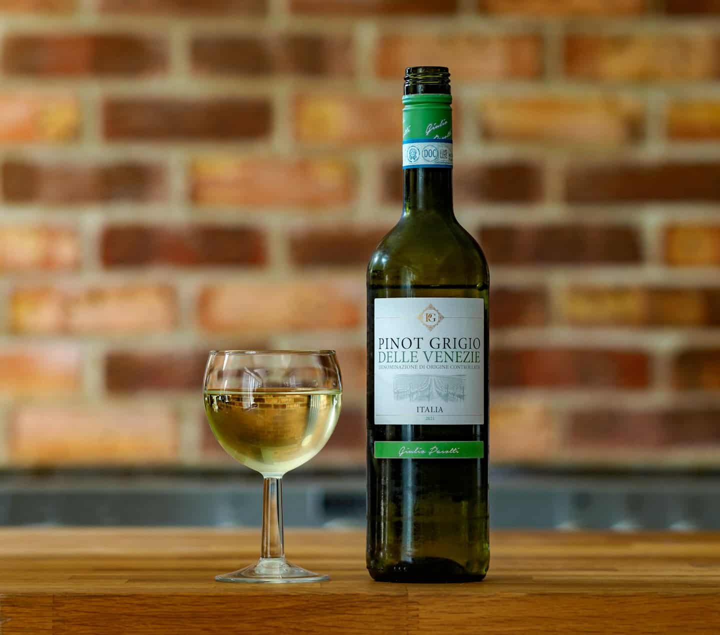 Una bottiglia di vino e un bicchiere sono su un tavolo di legno.